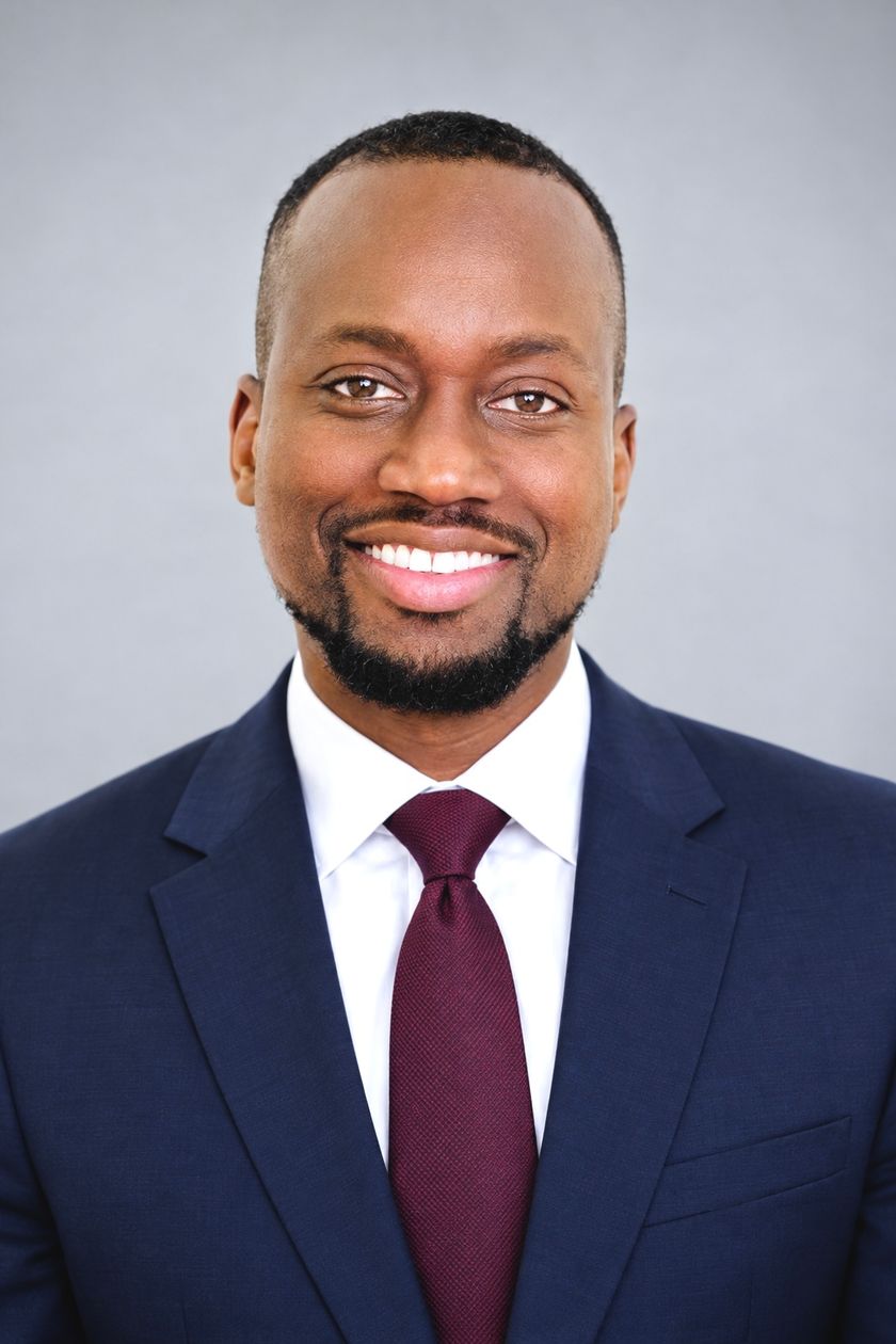 Portrait d'Aliou Gueye, souriant, en costume bleu marine
